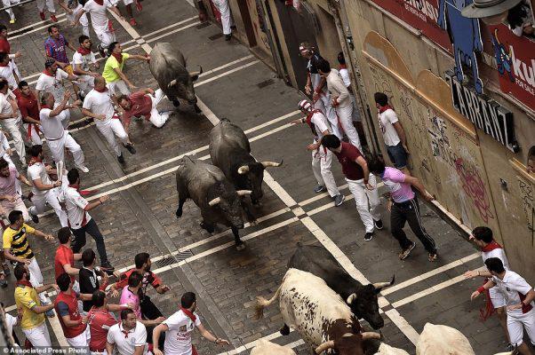 Revelers run with Jose Escolar Gil's fighting bulls as they head towards Estafeta street during the third running of the bulls at the San Fermin Festival, in Pamplona, northern Spain, Saturday, July 9, 2016. Revelers from around the world flock to Pamplona every year to take part in the eight days of the running of the bulls. (AP Photo/Alvaro Barrientos)