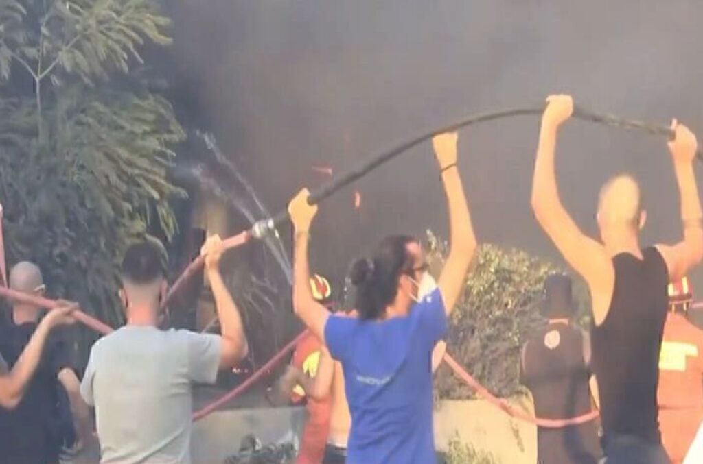 Φωτιά στην Αττική: Όλοι μαζί μία αλυσίδα – Συγκλονιστική φωτογραφία εθελοντών που κρατούν τη μάνικα
