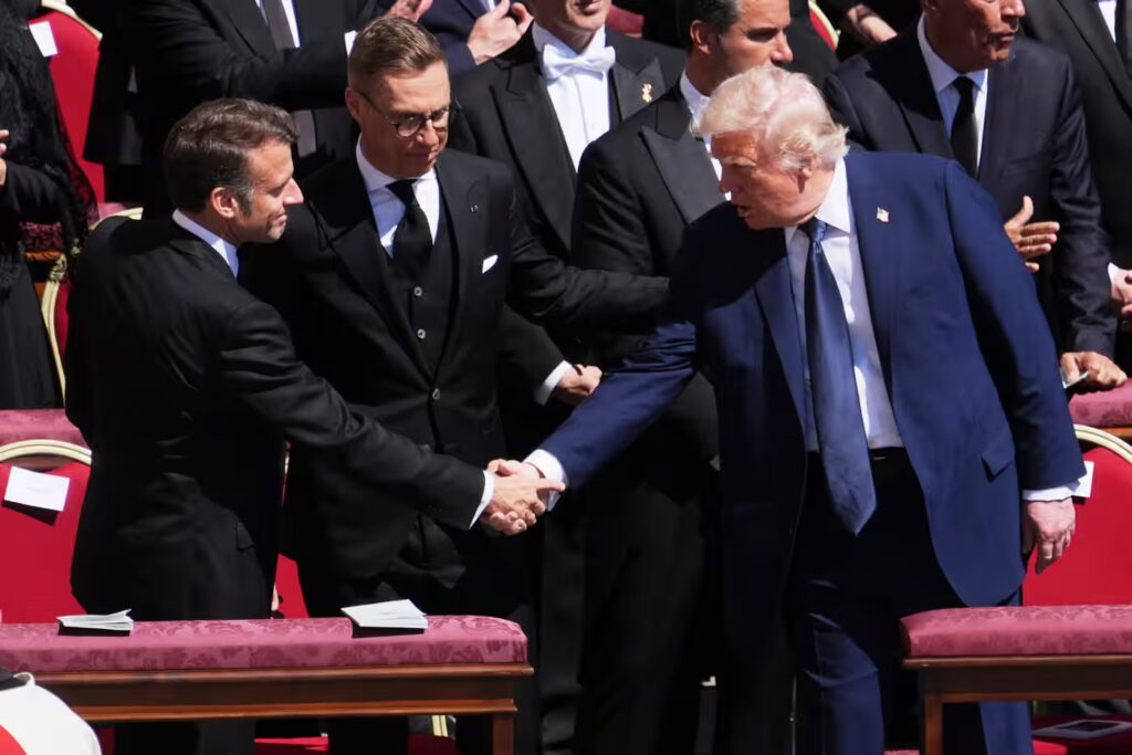 US president Donald Trump, right, shakes hands with French president Emmanuel Macron, left, as Finland's president Alexander Stubb, looks on, as they attend the funeral of Pope Francis. Photograph: Evan Vucci/AP