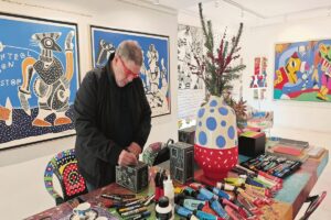 Ο Θανάσης Λάλας στο γεμάτο χρώμα γραφείο του, όπως μεταφέρθηκε στην γκαλερί Contemporary Athens.