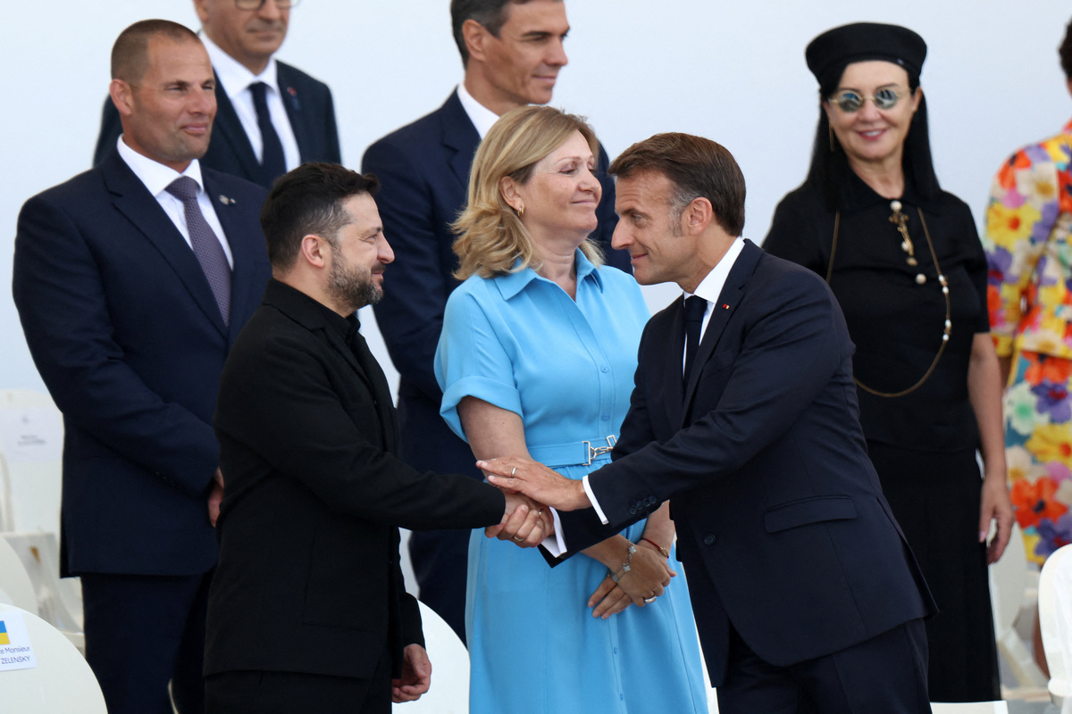 Ο Γάλλος πρόεδρος Εμανουέλ Μακρόν σφίγγει το χέρι του προέδρου της Ουκρανίας Βολοντίμιρ Ζελένσκι, δίπλα στην πρόεδρο της Εθνοσυνέλευσης Γιαέλ Μπράουν-Πιβέ, κατά τη διάρκεια της ετήσιας στρατιωτικής παρέλασης για την Ημέρα της Βαστίλης στο Παρίσι. REUTERS/Tom Nicholson