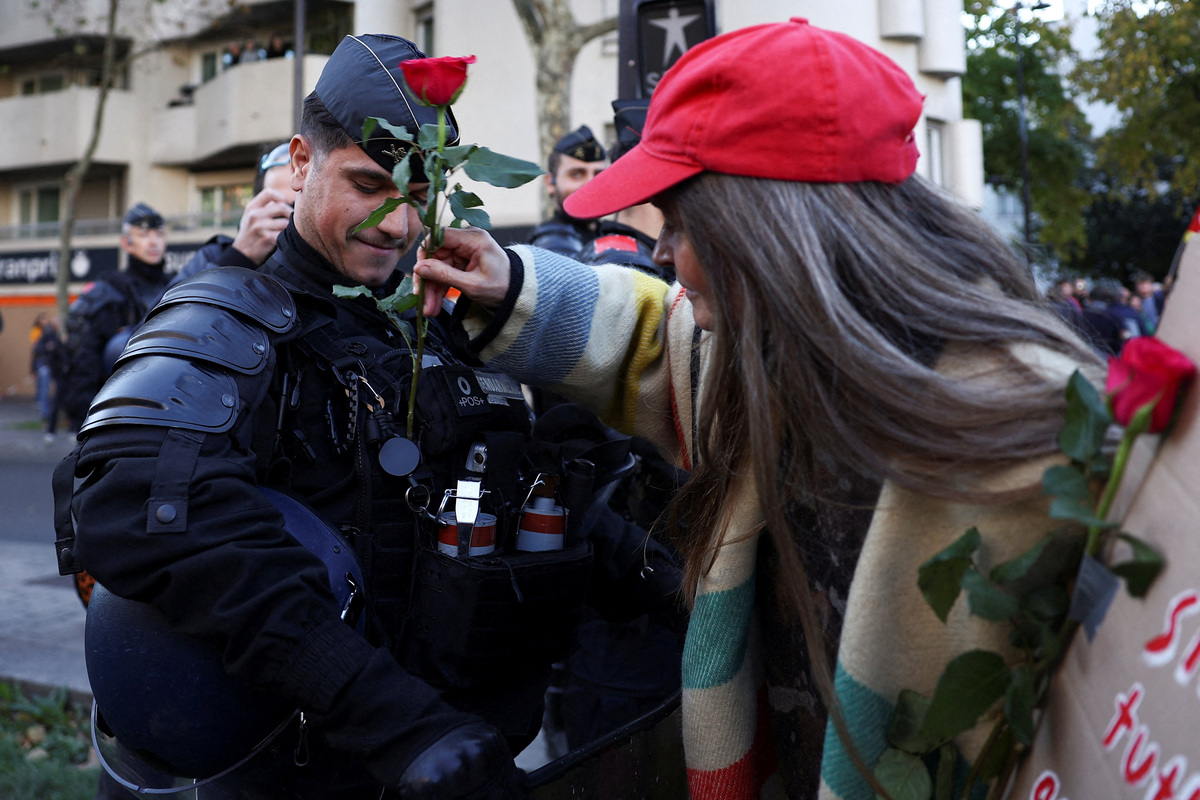 Διαδηλώτρια δίνει ένα λουλούδι σε αστυνομικό στις διαδηλώσεις στη Γαλλία.
